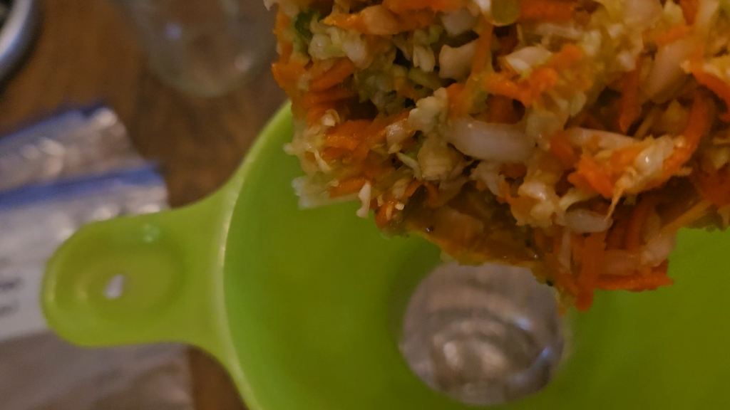 Ladling freezer slaw through a canning funnel into a freezer bag.