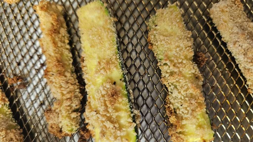 Crispy breaded zucchini on an air fryer tray.