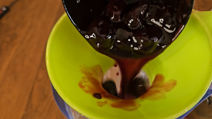 freezer cherry pie filling being ladled into funnel.