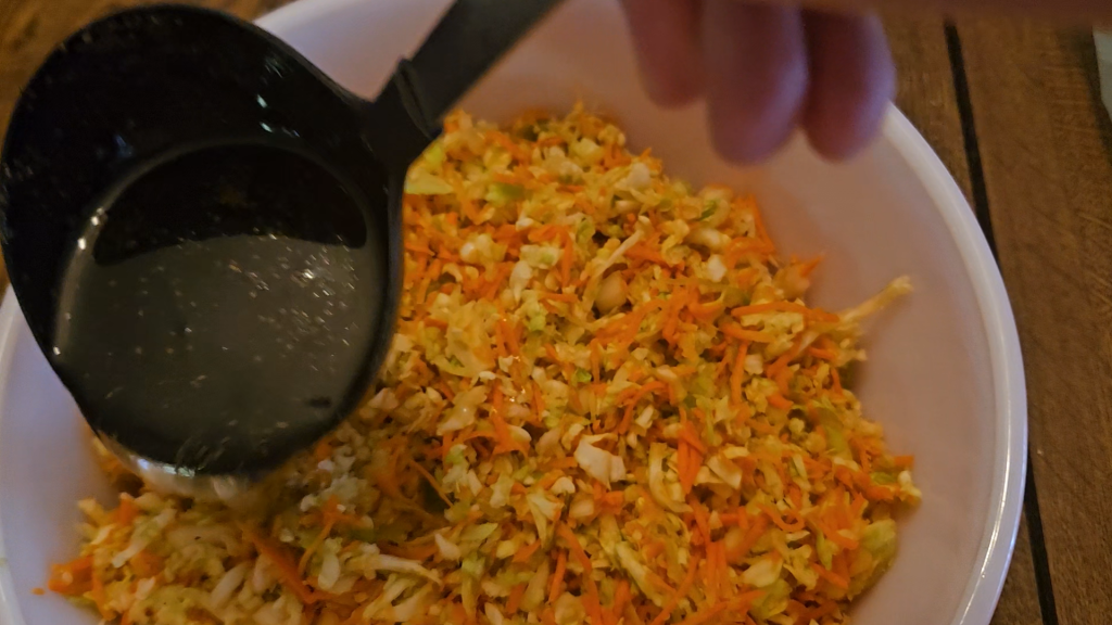 Ladling dressing over freezer slaw vegetables.