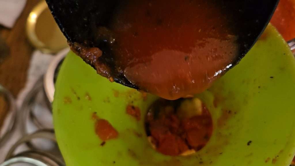 ladling tomato sauce into canning jar