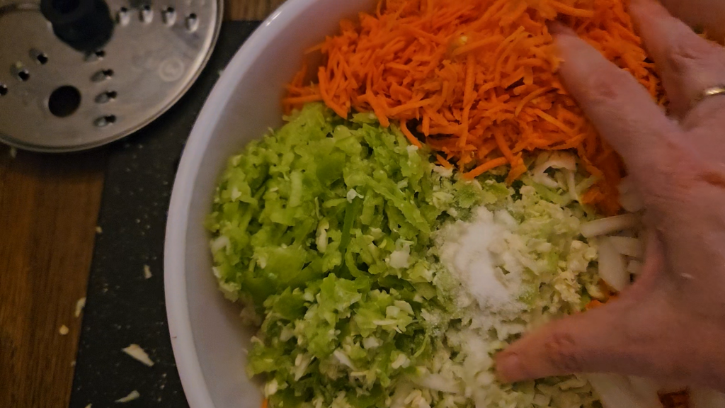 Mixing salt into the coleslaw ingredients.