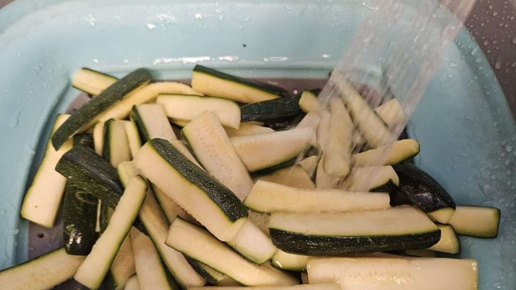 Rinsing the salt off of zucchini after sweating.