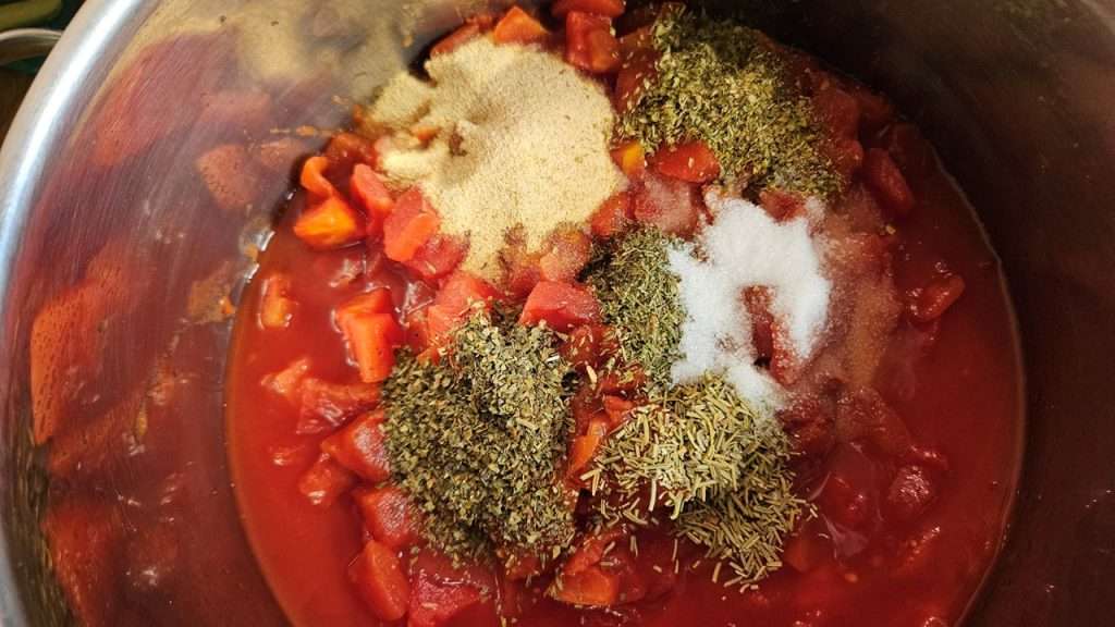 tomatoes and seasonings in a stainless steel pot.