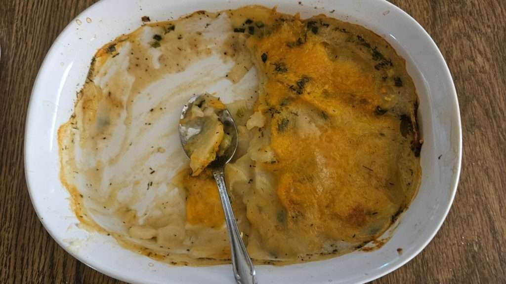 A casserole dish with fully cooked, half eaten scalloped potatoes