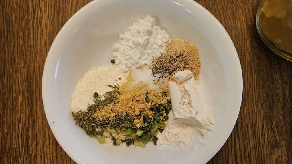 All of the dry ingredients for dehydrated scalloped potatoes including the flour, powdered milk, corn starch and spices in a bowl.