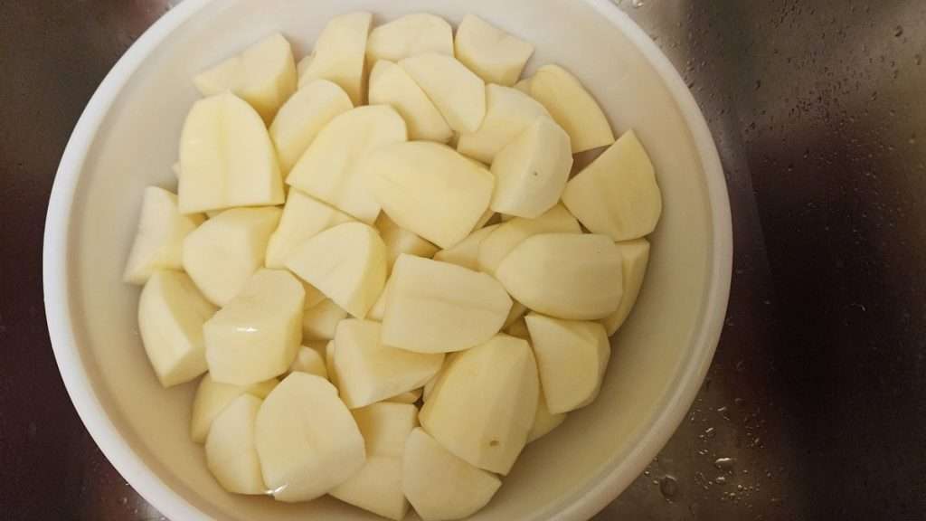 Cubed russet potatoes soaking in a bowl of water.