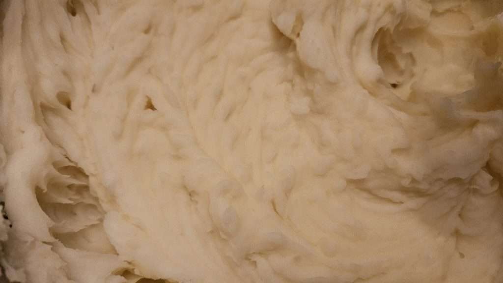 Close-up of smooth, lump-free mashed potatoes in a stainless steel pot.