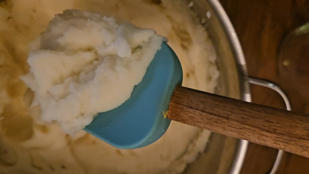 Rubber spatula holding mashed potatoes to show ideal texture for dehydrating.