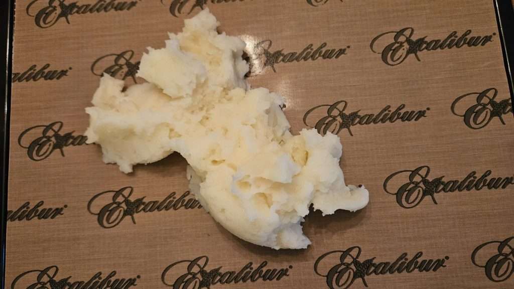 A scoop of mashed potatoes placed on a dehydrator tray before spreading