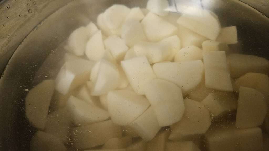 Large pot filled with cubed potatoes and water."