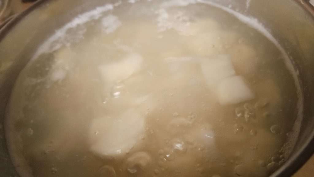 Cooked potatoes in water with some foam.