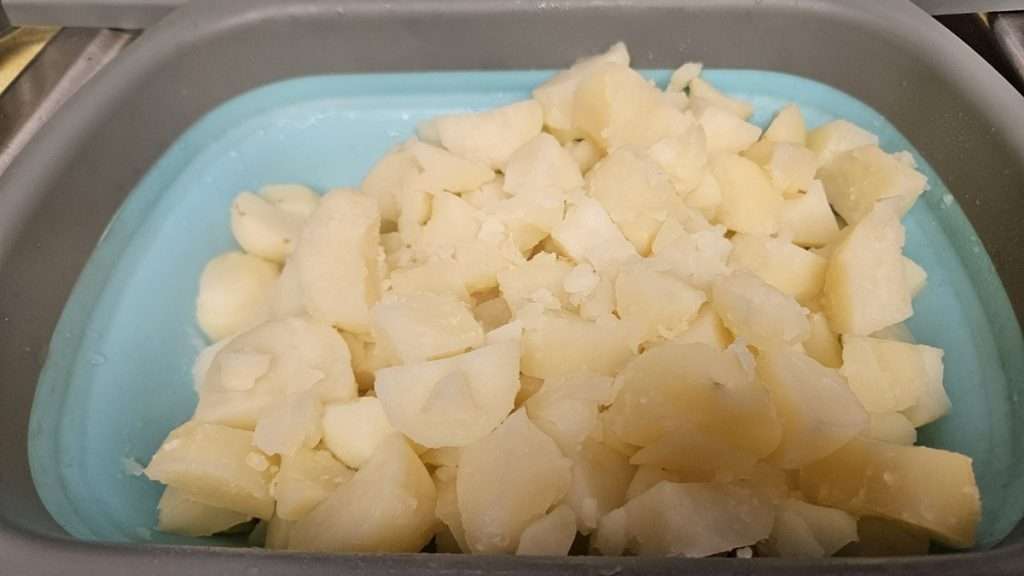 Boiled potatoes in a colander, some falling apart.
