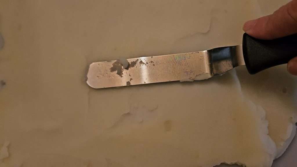 Offset spatula being used to spread mashed potatoes evenly on a dehydrator tray.