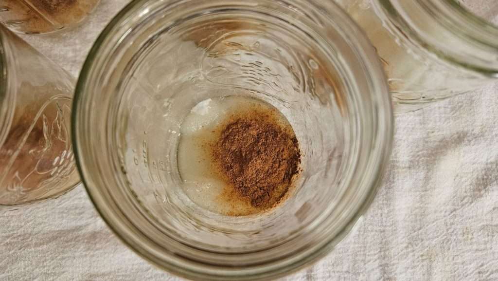 Overhead view of cinnamon added to a jar for sweet potato canning