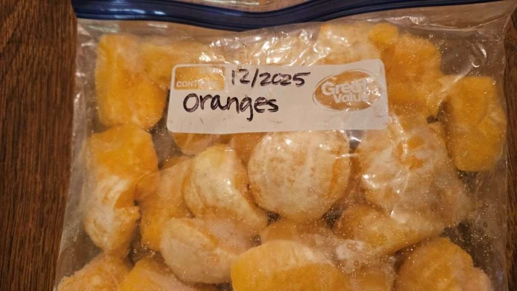 Orange sections after freezing, stored in a labeled freezer bag